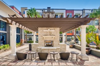 Poolside fireplace under a pergola with seating at EOS in Orlando, FL - Photo Gallery 4