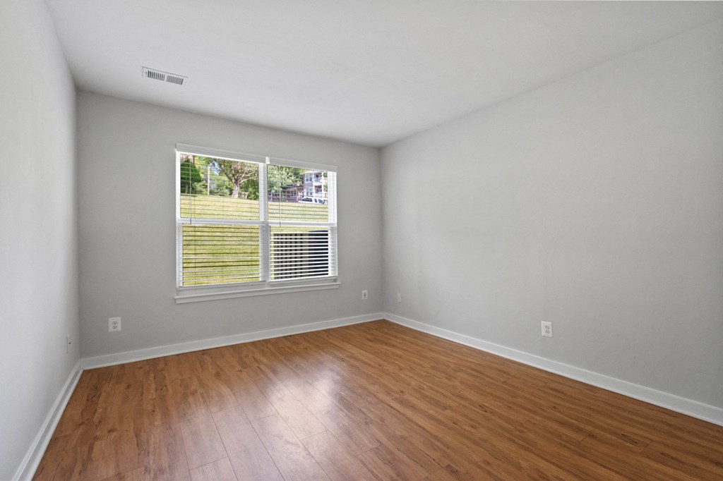a bedroom with hardwood floors and a large window