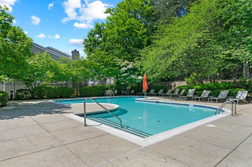 a swimming pool with chaise lounge chairs and trees in the background