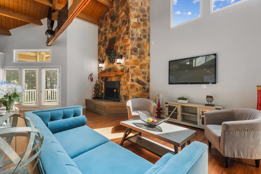 a large living room with a large stone fireplace and a flat screen tv - Photo Gallery