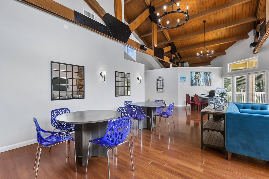a dining area with tables and chairs and a living room in the background
