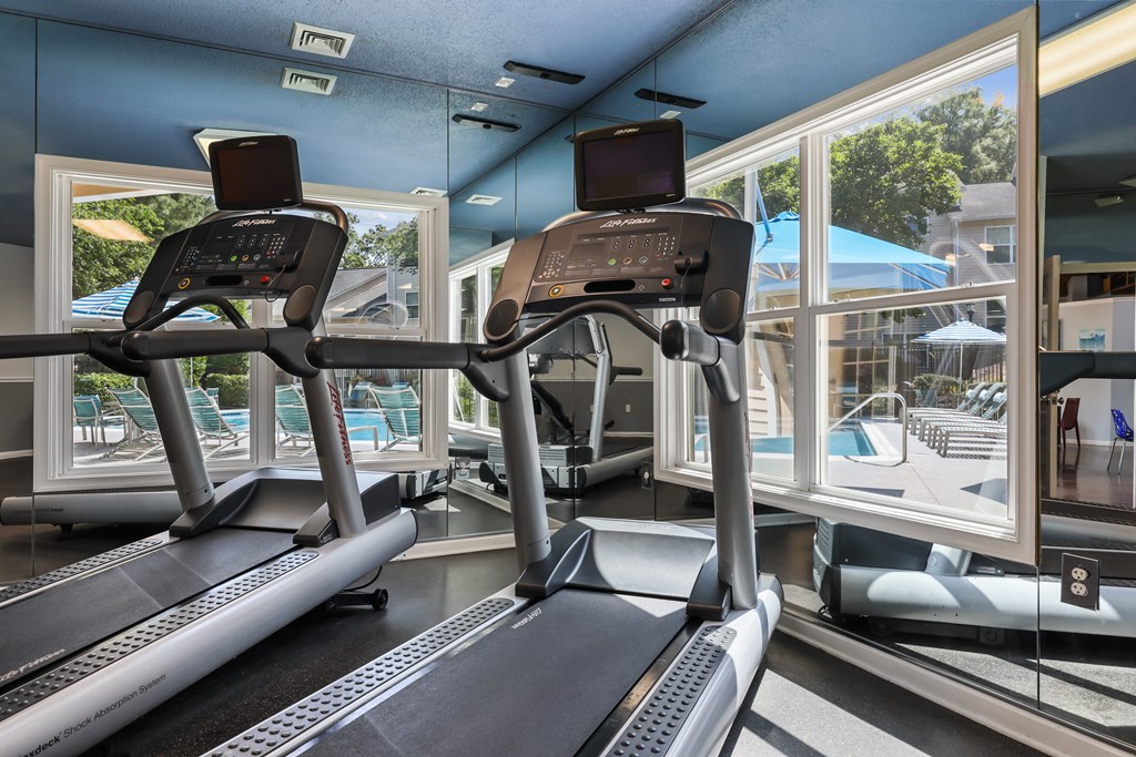 two treadmills in front of a window with a pool in the background