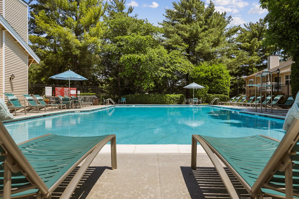 a swimming pool with lounge chairs and umbrellas