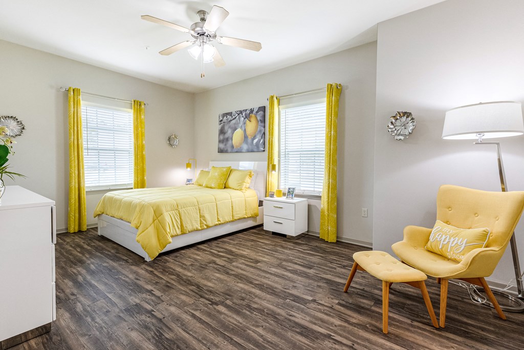 Spacious bedroom with two windows, wood-designed flooring and ceiling fan at Reagan Crossing in Covington, LA