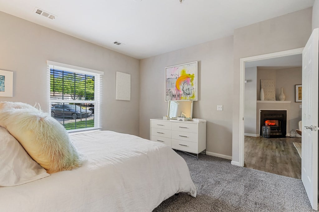 a bedroom with a bed and a dresser in front of a window