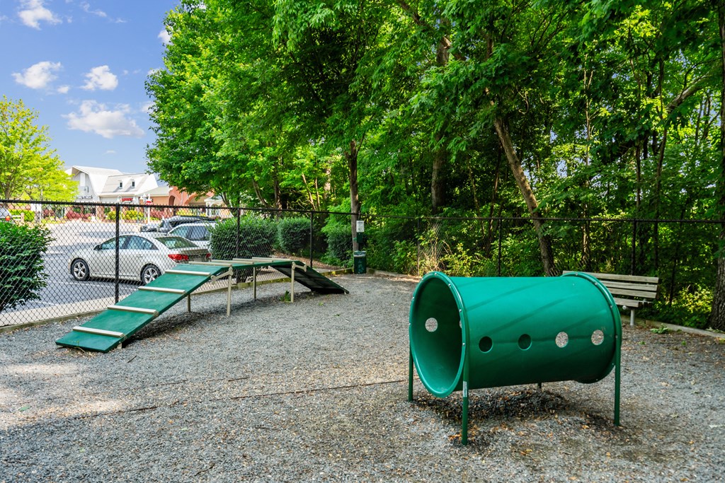 a playground with a green tube slide and bench