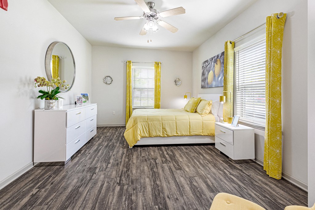 Spacious bedroom with windows, wood-designed flooring and ceiling fan at Reagan Crossing in Covington, LA