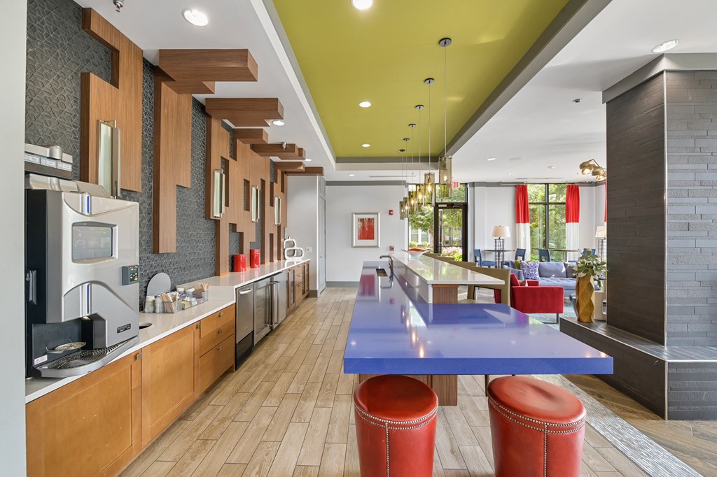 a communal kitchen with a blue table and red stools