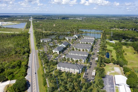 A bird's eye view of a highway running through a residential area with a large building on the right. at Allegra at Cocoa in Cocoa, FL, 32926