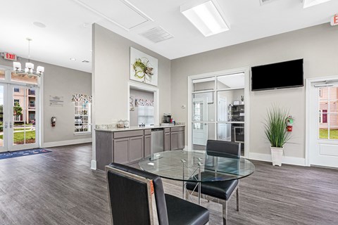 Interior of the leasing office and clubhouse with table and chairs and coffee maker at Reagan Crossing in Covington, LA