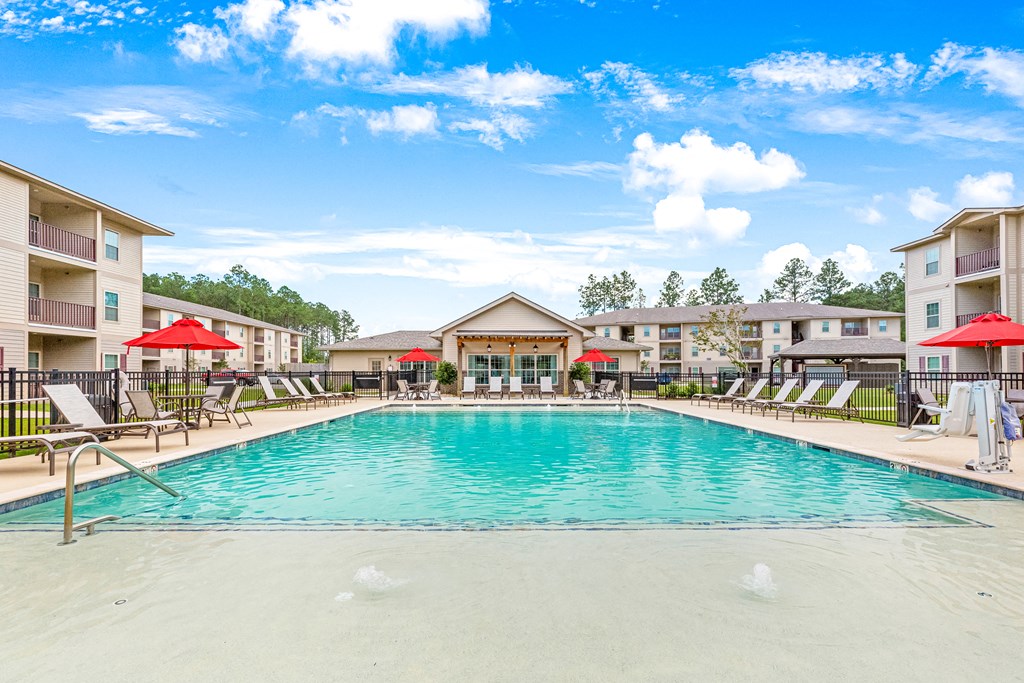 Resort-style swimming pool surrounded by lounge chairs and overlooking the clubhouse at Reagan Crossing in Covington, LA