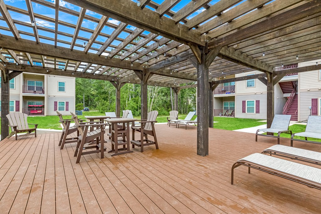 Outdoor lounge area with tables and chairs and shaded pergola at Reagan Crossing in Covington, LA