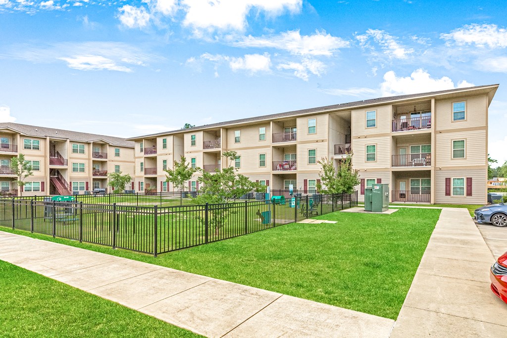 Leash-free bark park with agility equipment surrounded by residential buildings at Reagan Crossing in Covington, LA