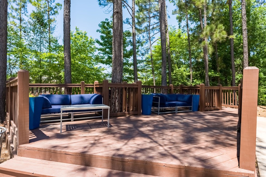 a deck with blue couches and chairs in the woods