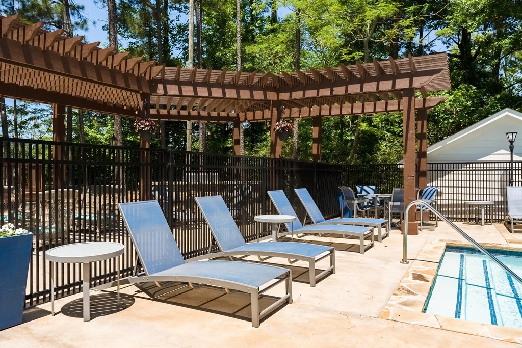 a resort style swimming pool with chaise lounge chairs and a pergola