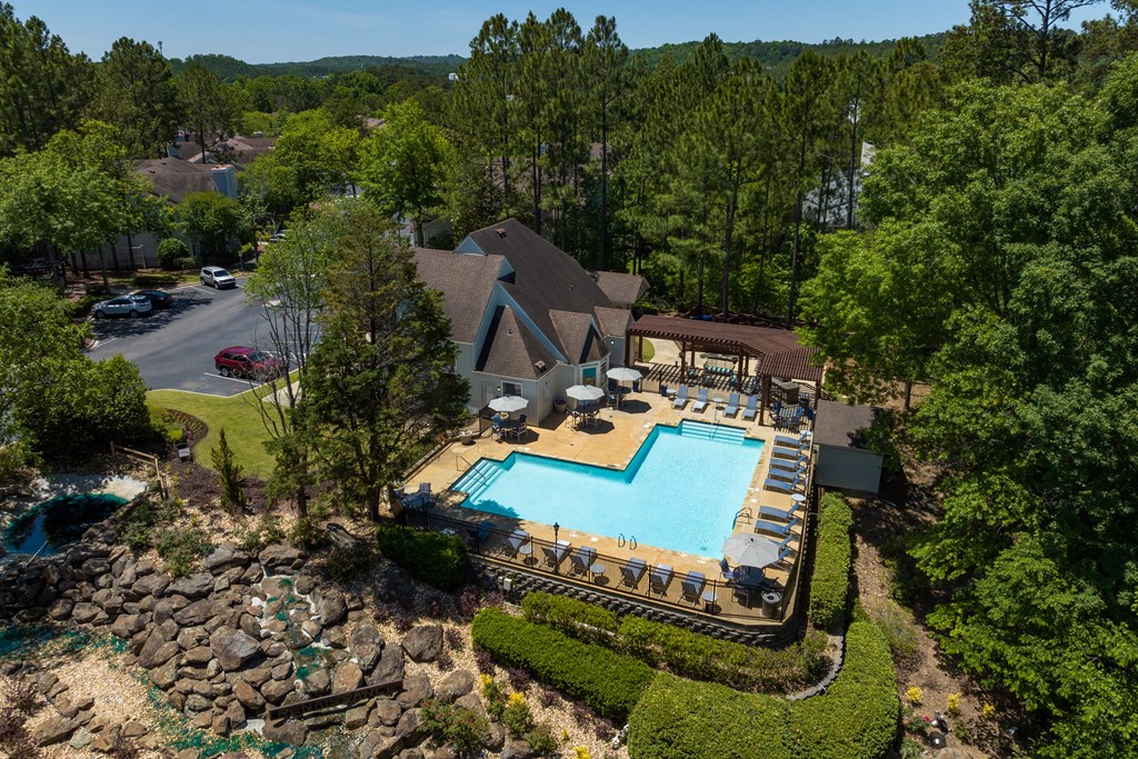 an aerial view of the resort style pool and hot tub with lounge chairs and umbrellas