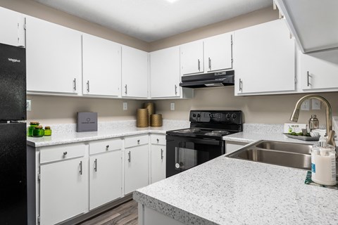 an updated kitchen with white cabinets and granite counter tops and black appliances