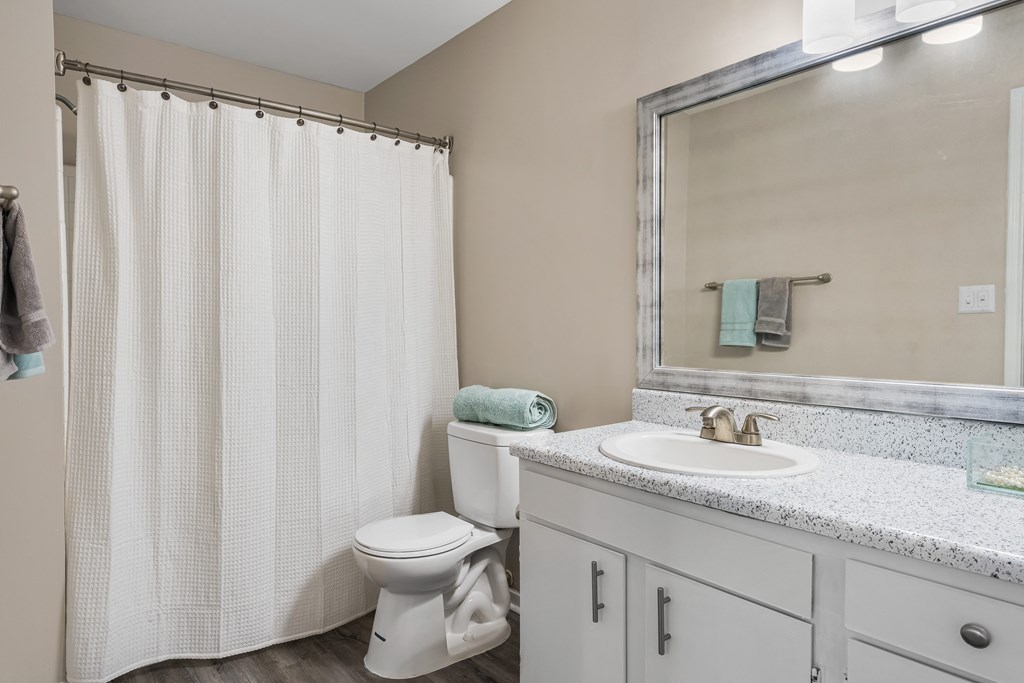 a bathroom with a white shower curtain and a white toilet next to a white sink and mirror