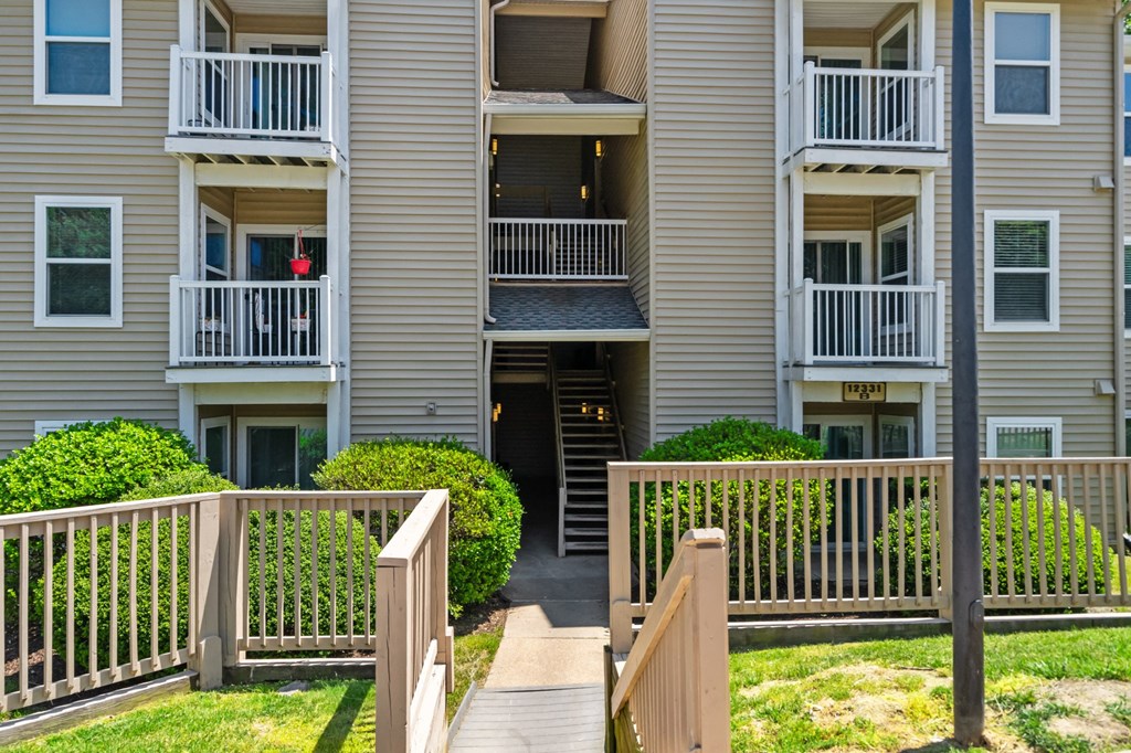 an exterior view of an apartment building with a wooden walkway leading to the front door