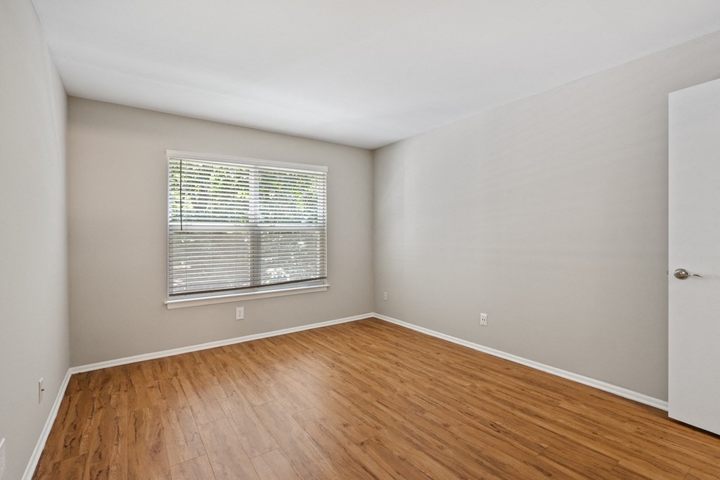 a bedroom with hardwood floors and a window