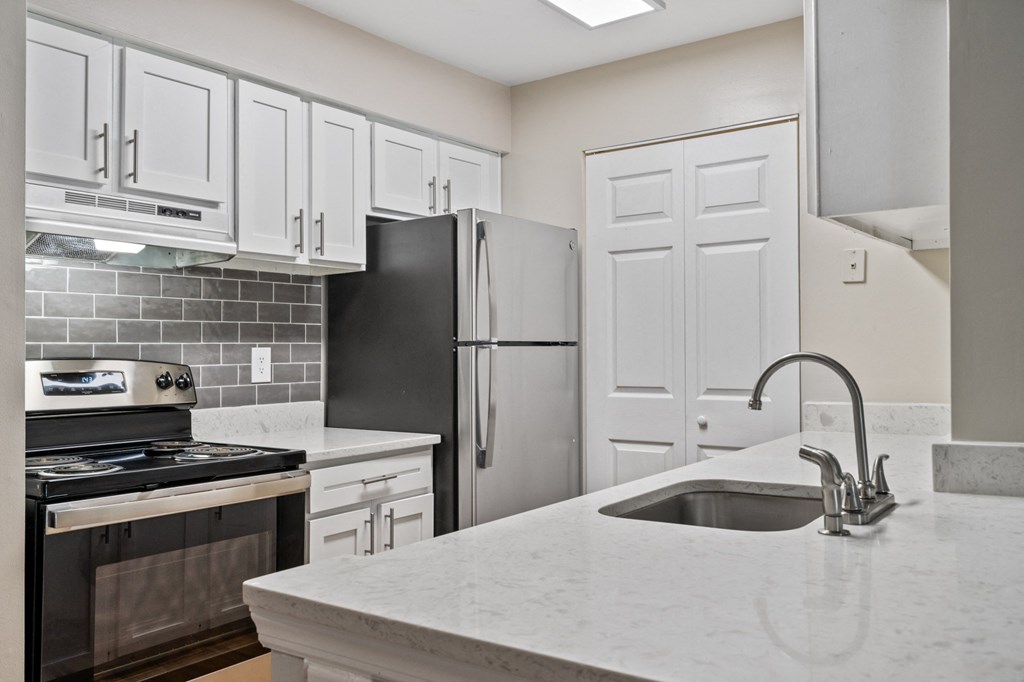 a kitchen with white cabinets and black appliances