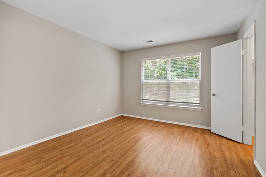 a bedroom with hardwood floors and a large window