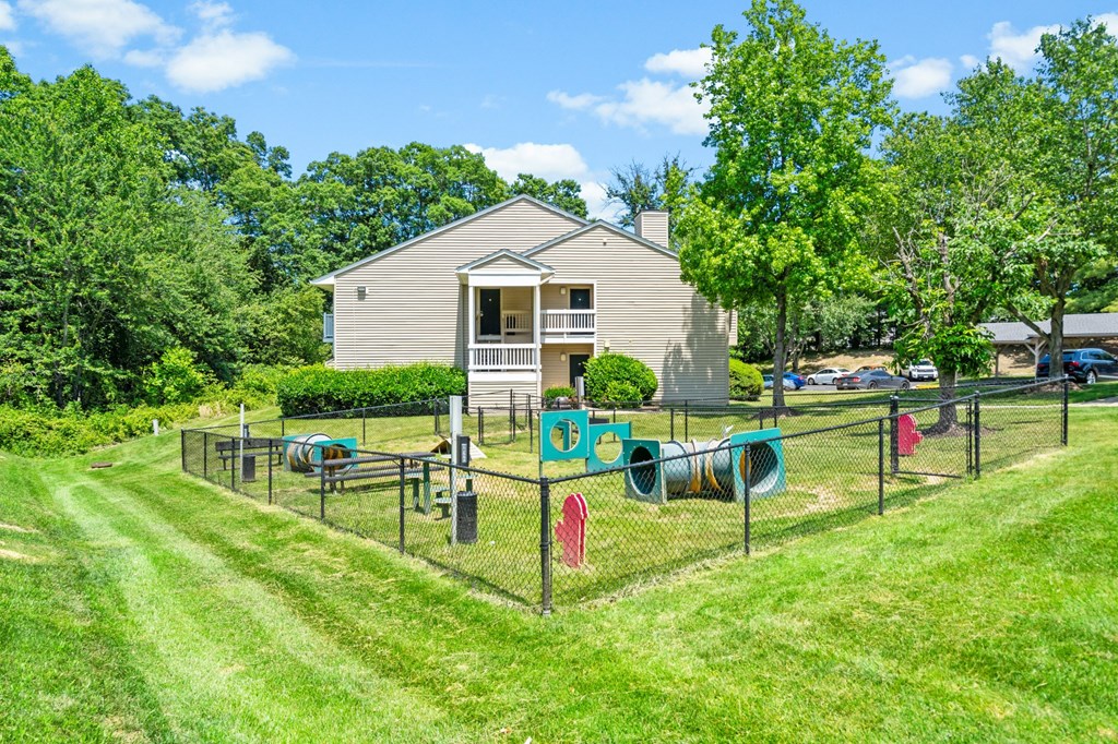 a fenced in area with laundry hanging on the line and a house in the background