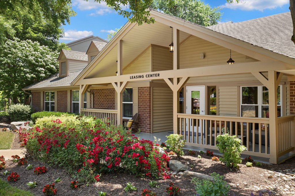 a building with a porch and flowers in front of it