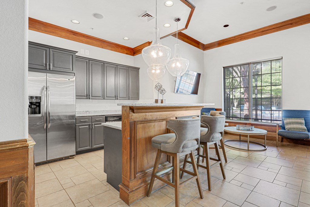 a kitchen with gray cabinets and a wooden island with three stools