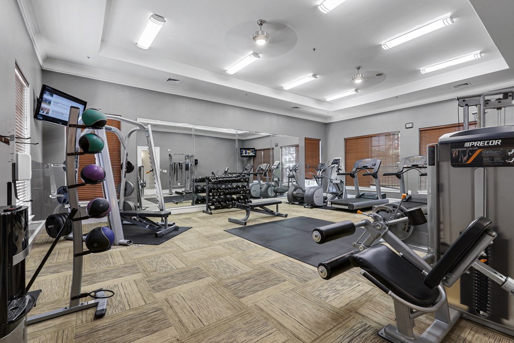 a spacious fitness center with cardio equipment and weights