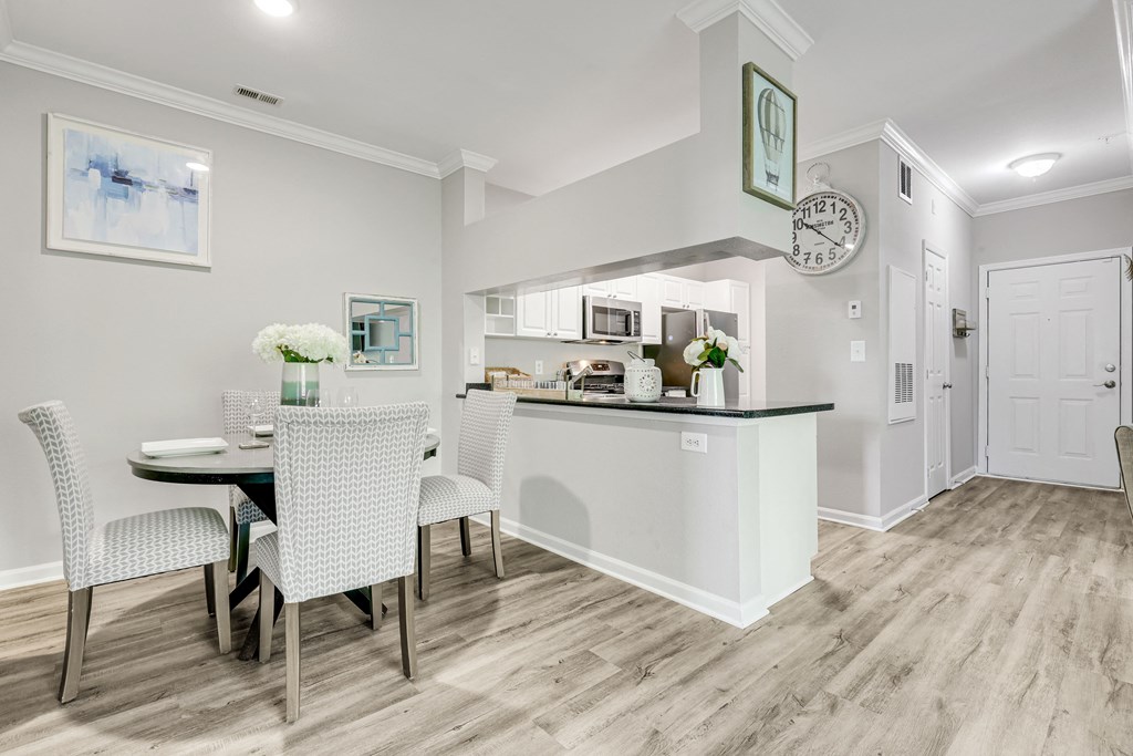 a dining area with a table and chairs and a kitchen in the background