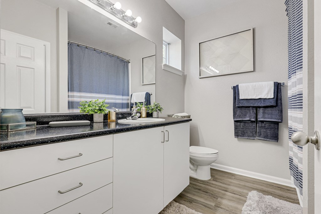 a bathroom with white cabinets and a black countertop