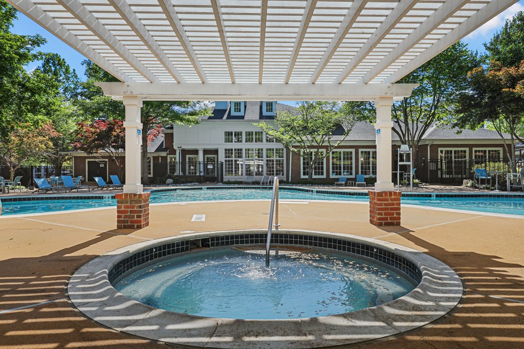 a pool with a fountain and a pergola in front of a building