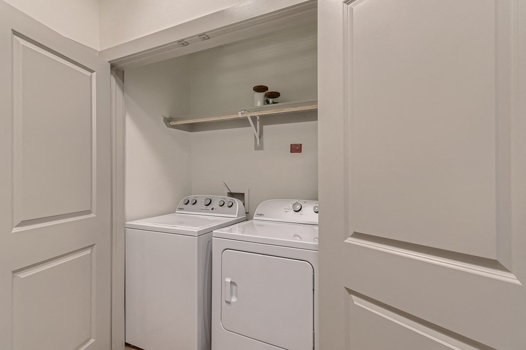 In-home laundry with full-size washer and dryer and built-in shelving at Cypress McKinney Falls in Austin, TX
