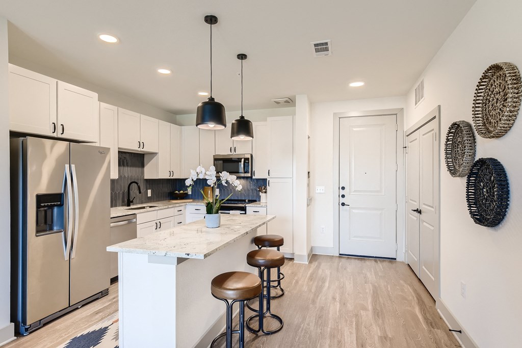 Open-concept kitchen with island bar with bar-style seating at Cypress McKinney Falls in Austin, TX