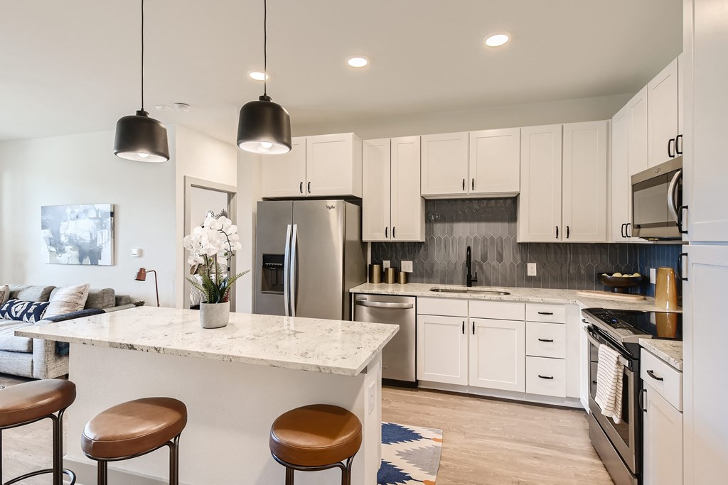 Kitchen with stainless steel appliances, granite counters, and island bar at Cypress McKinney Falls in Austin, TX