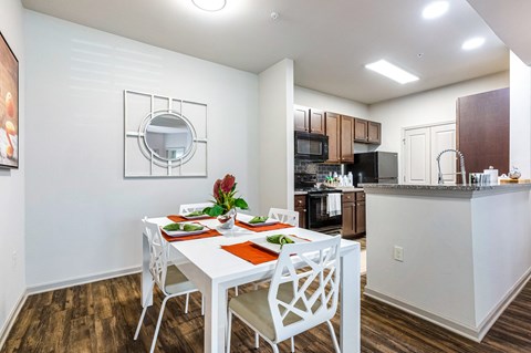 a dining room with a white table and chairs and a kitchen