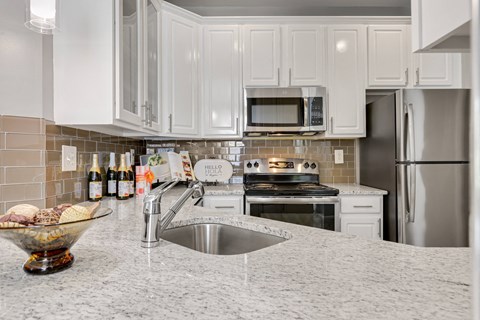 a kitchen with white cabinets and granite countertops
