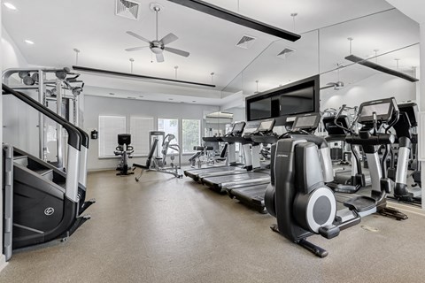 a gym with cardio equipment and a flat screen tv