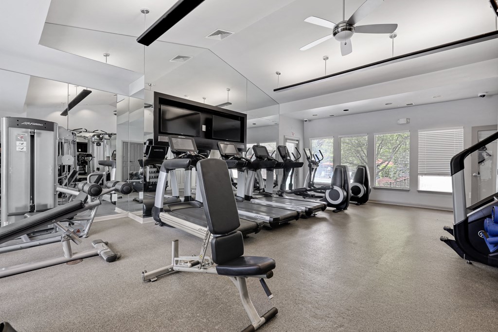 a gym with cardio equipment and a flat screen tv