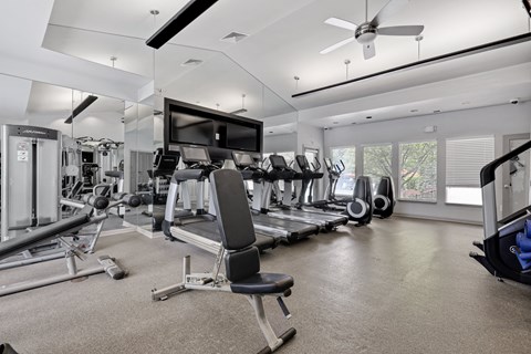a gym with cardio equipment and a flat screen tv