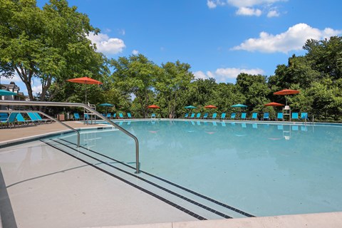 a large swimming pool with umbrellas and chairs around it
