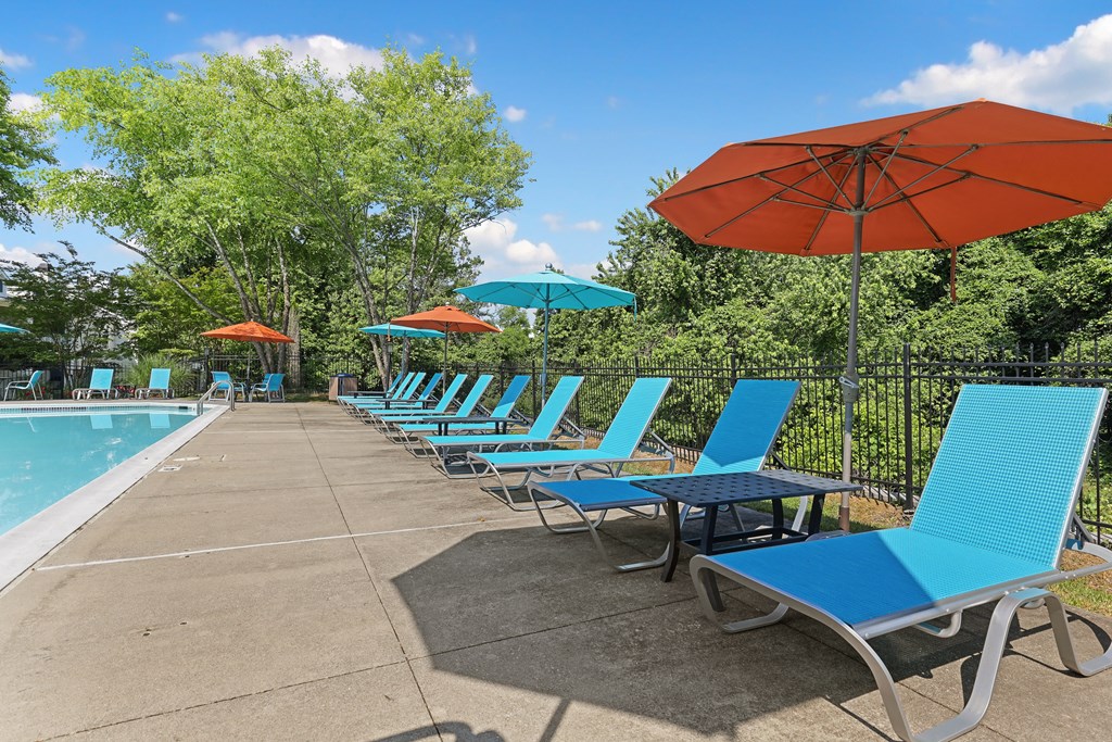 a row of blue chaise lounges and umbrellas next to a swimming pool