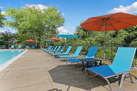 a row of blue chaise lounges and umbrellas next to a swimming pool