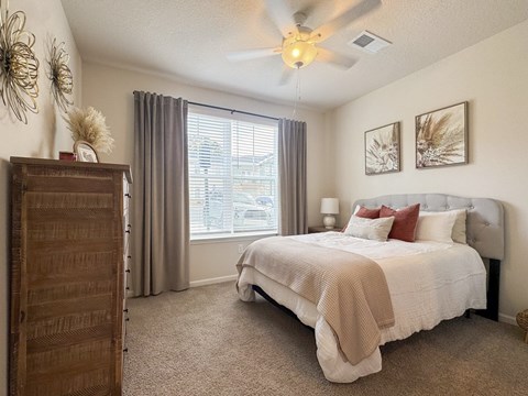 Spacious bedroom with tufted headboard and ceiling fan at The Maxwell Apartments, Georgia