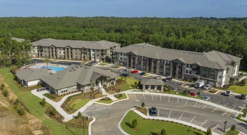 Welcome to The Retreat at Fairhope Village in Fairhope, AL. The community features a large entry drive, leasing center building, pool, and residential buildings. - Photo Gallery 1