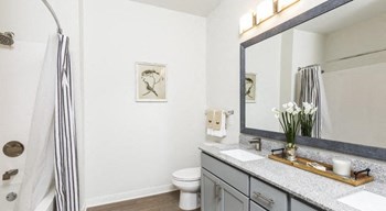 Model bathroom with large mirror and double sink vanity at The Retreat at Fairhope Village in Fairhope, AL