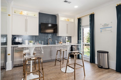 a kitchen with bar stools and a counter with a sink and a television