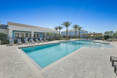 A swimming pool surrounded by a tiled patio and lounge chairs.at Allegra at Cocoa in Cocoa, FL, 32926