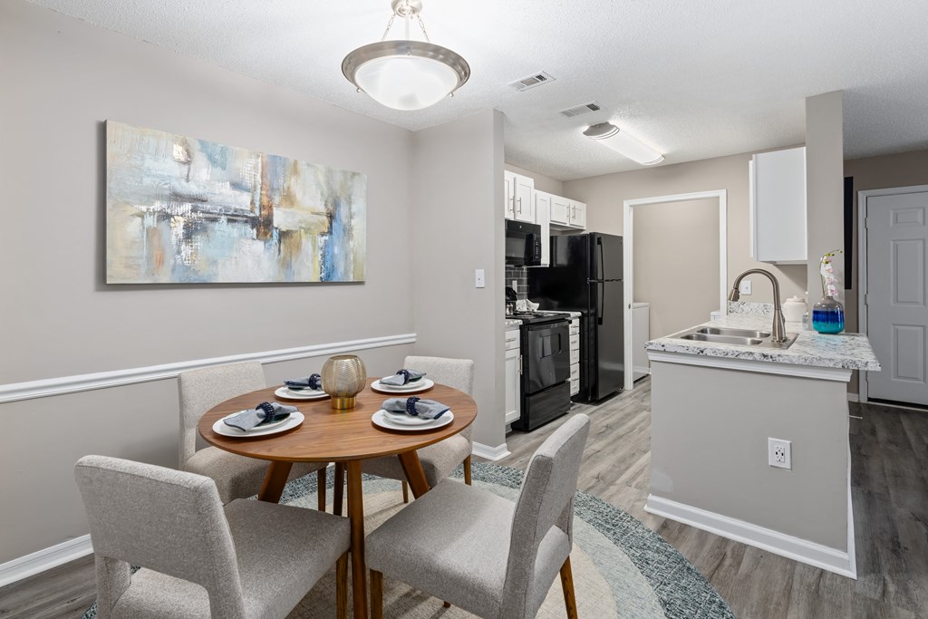 a dining area with a table and chairs and a kitchen in the background